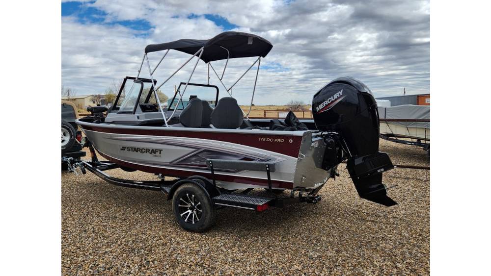 Starcraft fishing boat parked on gravel under cloudy sky