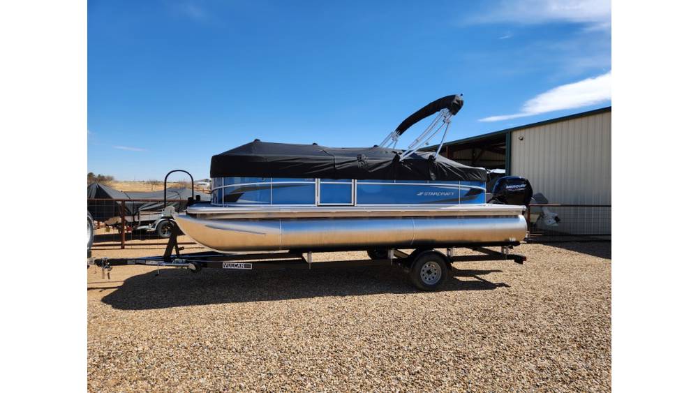 Pontoon boat parked near barn on sunny day