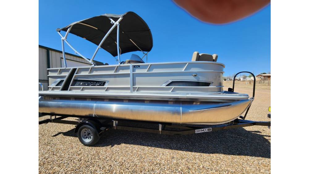 Silver pontoon boat with canopy parked on trailer